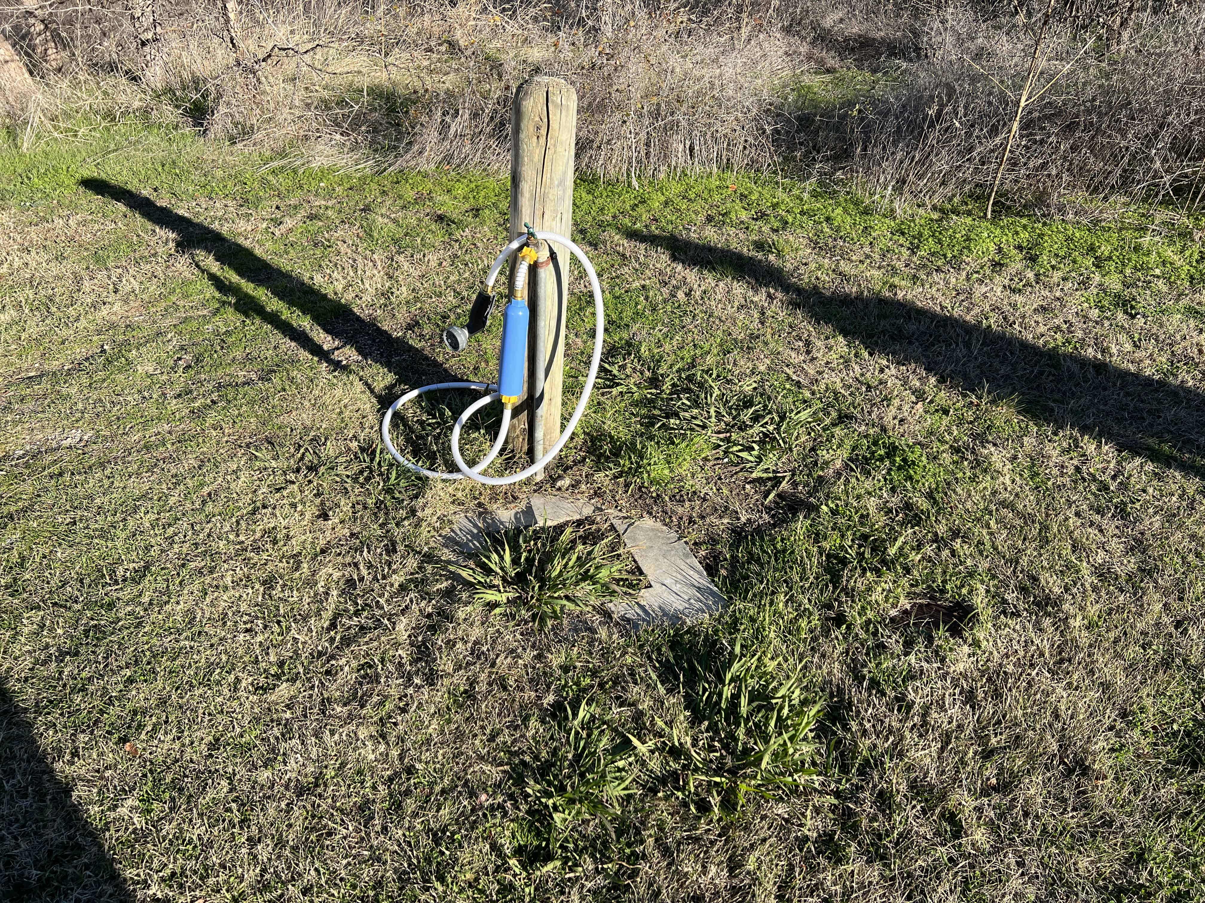 an outdoor camping shower attached to water line at a campground 