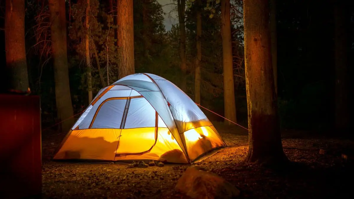 a tent in a forest at night with people changing into what they wear for bed camping