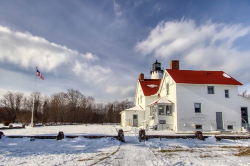 This is a photograph of Port Iroquois Lighthouse located in Hiawatha National Forest during the winter and covered in snow.