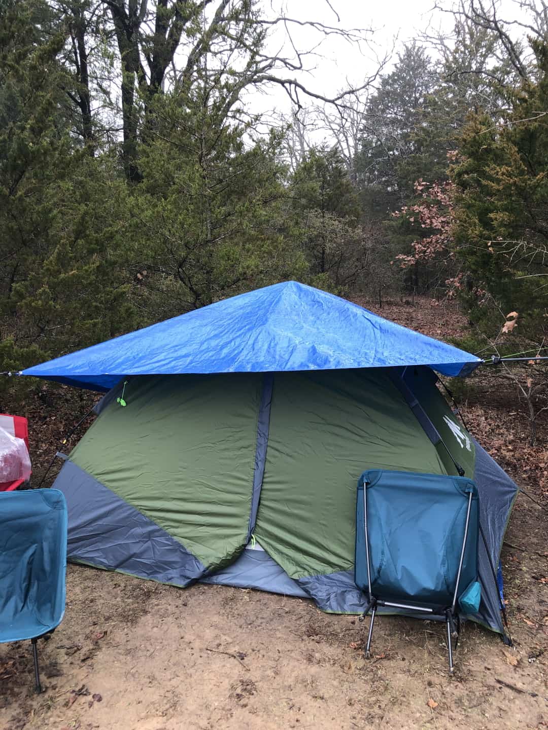 A pop-tent with an additional tarp tied over the tent to prevent rain from hitting the tent